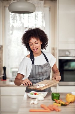 Önlüklü, gülen, sebzeli mantarlı melez bir kadın. Mutfağın içi..