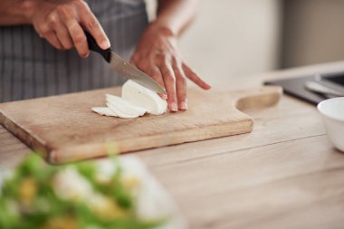 Mutfakta ayakta ve mantar doğranan önlük karışık ırk kadın yakın çekim.