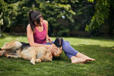 Genç, çekici, formda bir Yogi esmer arka bahçede köpeğiyle oynuyor..