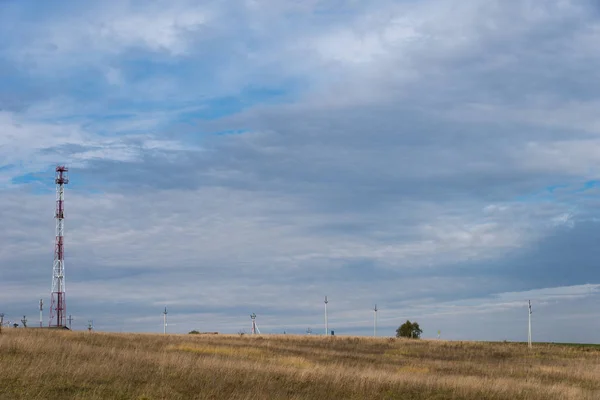 Autumn field with electric towers and mobile phone tower