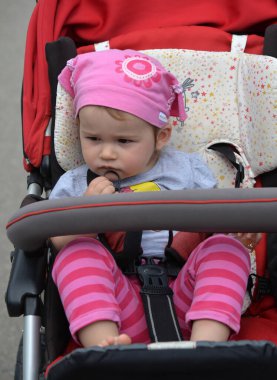 Kırmızı bebek arabalı küçük kız yaz yürüyüşünde.