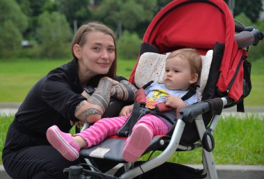 Küçük kız yaz yürüyüşünde annesiyle bebek arabasında.