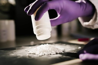 Bir bilim adamının elleri haplarla dolu tencereyi boşaltıyor.