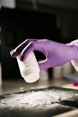 Bir bilim adamının elleri haplarla dolu tencereyi boşaltıyor.