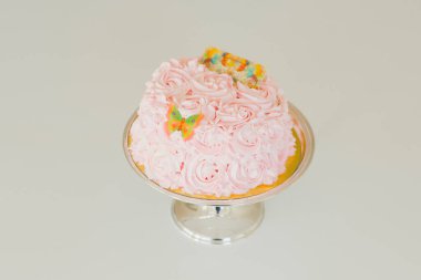 Pembe doğum günü pastası, pembe çiçeklerle süslenmiş.