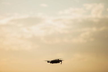 Sunset 'te uçan bir dronun silueti.