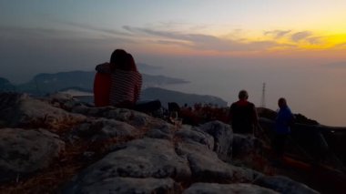 Pimonte, İtalya. 16 Ağustos 2020. Faito Dağı. Dağın tepesinde genç bir çift gün batımında Napoli Körfezi 'nin ve Sorrento sahilinin nefes kesici manzarasıyla önlerinde oturuyorlar..