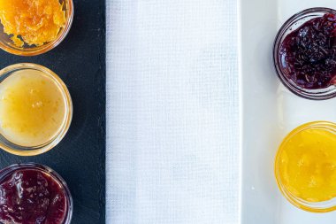 Angri, İtalya. Beyaz bir tabağa farklı tipte reçel içeren küçük kaseler ve ortasında beyaz fotokopi alanı olan tahta kesme tahtası..