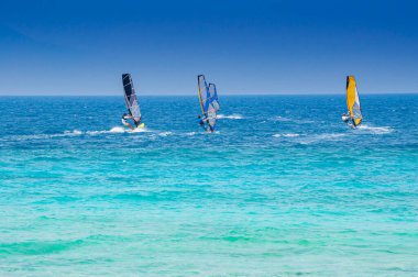 Lefkada, Yunanistan. 18 Ağustos 2011. Yunanistan 'ın Lefkada kentindeki Agios Ioannis körfezinde, zümrüt yeşili bir denizde ve açık bir gökyüzünde bazı insanlar rüzgar sörfü yapıyor..