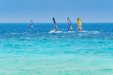 Lefkada, Yunanistan. 18 Ağustos 2011. Yunanistan 'ın Lefkada kentindeki Agios Ioannis körfezinde, zümrüt yeşili bir denizde ve açık bir gökyüzünde bazı insanlar rüzgar sörfü yapıyor..