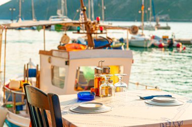 Lefkada, Yunanistan. 18 Ağustos 2011. Vassiliki Körfezi. Rıhtıma yanaşmış balıkçı teknesi olan deniz kenarında bir restoranın masası..
