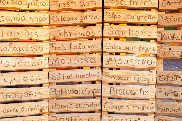 Lefkada, Greece. August 18th, 2011. A restaurant displays the dishes that can be served in different languages on wooden panels.