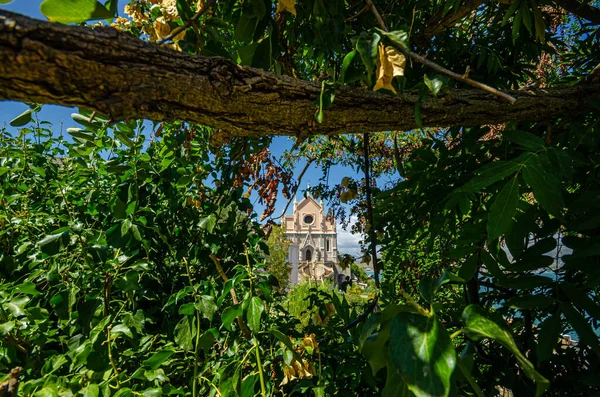 Gaeta, İtalya. 12 Ağustos 2017. San Francesco Kilisesi 'nden Gaeta' nın ağaçlar ve yapraklar arasındaki görüntüsü. Bu kilise şehrin tarihi merkezinde yer almaktadır ve 1283 yılından itibaren inşa edilmiştir..