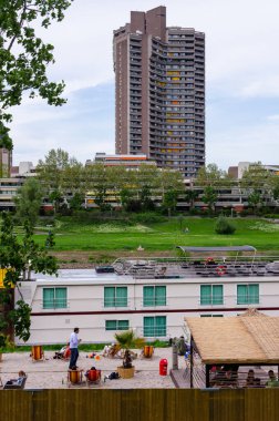 Mannheim, Almanya. 30 Nisan 2010. Neckarstadt-West bölgesindeki Nackar Nehri boyunca yerleşik gökdelenler. Ön planda insanların gevşeyip içki içtiği bir şehir plajı var..