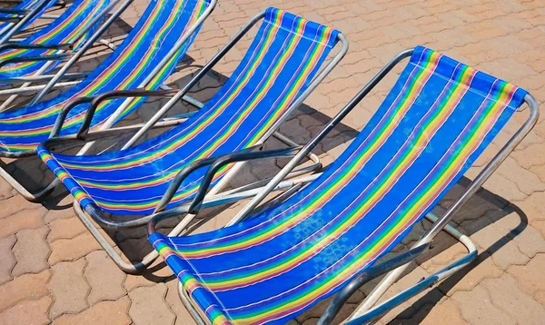 地板上的条纹沙滩椅 在阳光下的躺椅 暑假假期概念 — 图库照片