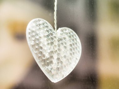 Cam bir plaka üzerinde asılı Mobil plastik kalp şeklinde. Metninizi yerleştirmek için alan içeren seçici odaklama.