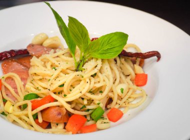 Baharatlı kızarmış spagetti jambonu ya da kırmızı biberli bolonez ve beyaz tabakta fesleğen yaprağı. Sağlıklı makarna.. 