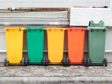 Kaldırımda farklı renklerde çöp bidonları var. Çevre için Eski Geri Dönüşüm Çöpü.