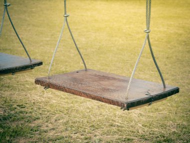 Bahçede ya da parkta asılı ahşap salıncak. Kapat.