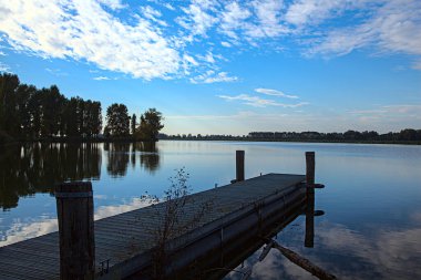 Gün batımında göl kıyısında, gökyüzü suya gömülmüş.