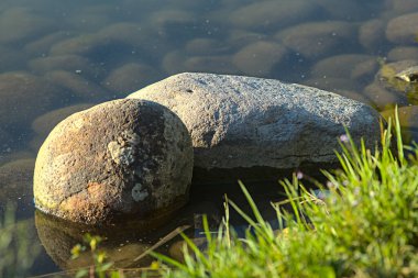 Gün batımında bir gölün kıyısında taşlar