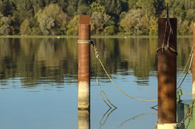 Gün batımında bir limanın kutupları ve suya yansıyan yansımaları.