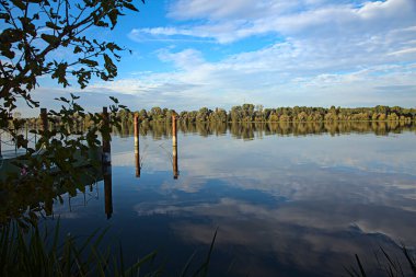Gün batımında bir limanın kutupları ve suya yansıyan yansımaları.