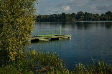 Sonbaharın başlarında, açık bir günde, bir gölün kıyısında yüzer halde.