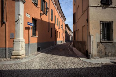 Yol, binaların arasındaki mesafeye kadar uzanan gölgede kısmen kaldırımlı bir sokağa erişim.