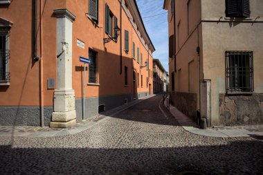 Yol, binaların arasındaki mesafeye kadar uzanan gölgede kısmen kaldırımlı bir sokağa erişim.