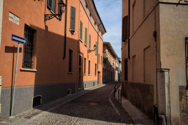Yol, binaların arasındaki mesafeye kadar uzanan gölgede kısmen kaldırımlı bir sokağa erişim.