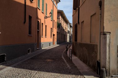 Yol, binaların arasındaki mesafeye kadar uzanan gölgede kısmen kaldırımlı bir sokağa erişim.