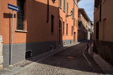 Yol, binaların arasındaki mesafeye kadar uzanan gölgede kısmen kaldırımlı bir sokağa erişim.