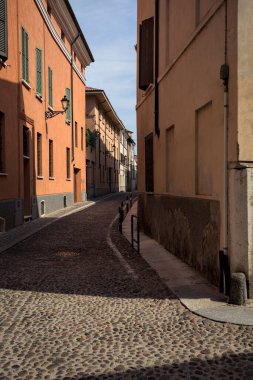Yol, binaların arasındaki mesafeye kadar uzanan gölgede kısmen kaldırımlı bir sokağa erişim.