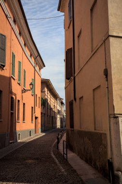 Yol, binaların arasındaki mesafeye kadar uzanan gölgede kısmen kaldırımlı bir sokağa erişim.