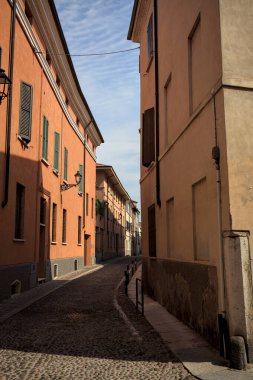 Yol, binaların arasındaki mesafeye kadar uzanan gölgede kısmen kaldırımlı bir sokağa erişim.