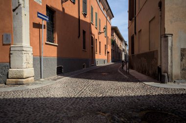 Yol, binaların arasındaki mesafeye kadar uzanan gölgede kısmen kaldırımlı bir sokağa erişim.