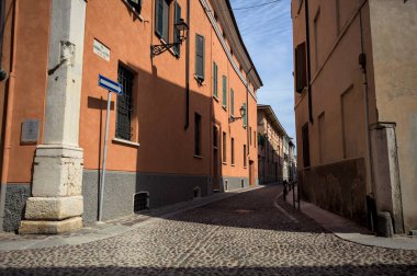 Yol, binaların arasındaki mesafeye kadar uzanan gölgede kısmen kaldırımlı bir sokağa erişim.