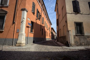 Yol, binaların arasındaki mesafeye kadar uzanan gölgede kısmen kaldırımlı bir sokağa erişim.