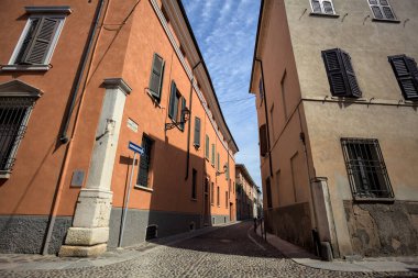 Yol, binaların arasındaki mesafeye kadar uzanan gölgede kısmen kaldırımlı bir sokağa erişim.