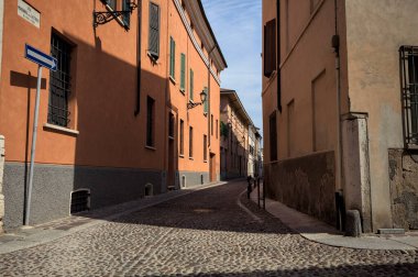 Yol, binaların arasındaki mesafeye kadar uzanan gölgede kısmen kaldırımlı bir sokağa erişim.