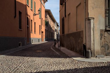 Yol, binaların arasındaki mesafeye kadar uzanan gölgede kısmen kaldırımlı bir sokağa erişim.