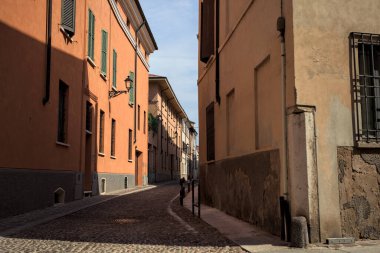 Yol, binaların arasındaki mesafeye kadar uzanan gölgede kısmen kaldırımlı bir sokağa erişim.