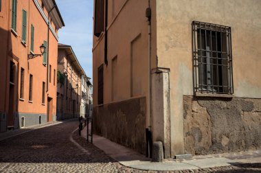 Yol, binaların arasındaki mesafeye kadar uzanan gölgede kısmen kaldırımlı bir sokağa erişim.