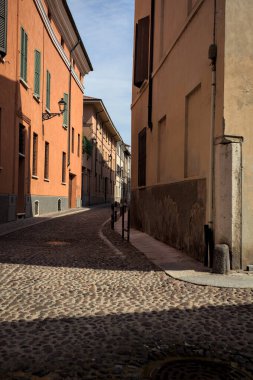 Yol, binaların arasındaki mesafeye kadar uzanan gölgede kısmen kaldırımlı bir sokağa erişim.