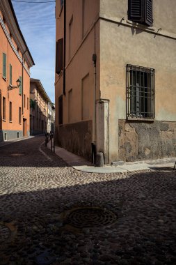 Yol, binaların arasındaki mesafeye kadar uzanan gölgede kısmen kaldırımlı bir sokağa erişim.