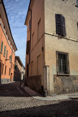 Yol, binaların arasındaki mesafeye kadar uzanan gölgede kısmen kaldırımlı bir sokağa erişim.