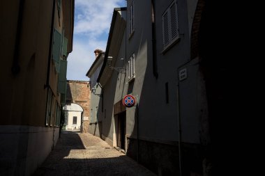 Yolun yarısı gölgede, güneşli bir günde güneşli bir İtalyan kasabasında açık bir kapı var.