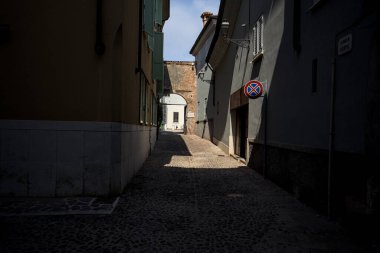 Yolun yarısı gölgede, güneşli bir günde güneşli bir İtalyan kasabasında açık bir kapı var.