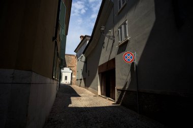 Yolun yarısı gölgede, güneşli bir günde güneşli bir İtalyan kasabasında açık bir kapı var.